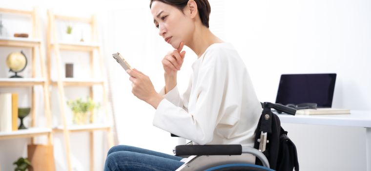車椅子に乗り携帯電話を眺めているような女性のイメージ