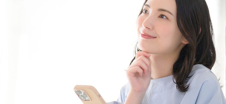 携帯電話を持って考え事をしているような女性のイメージ