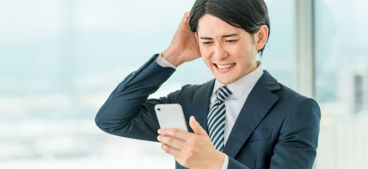 男性が携帯電話を見て困っているようなイメージ